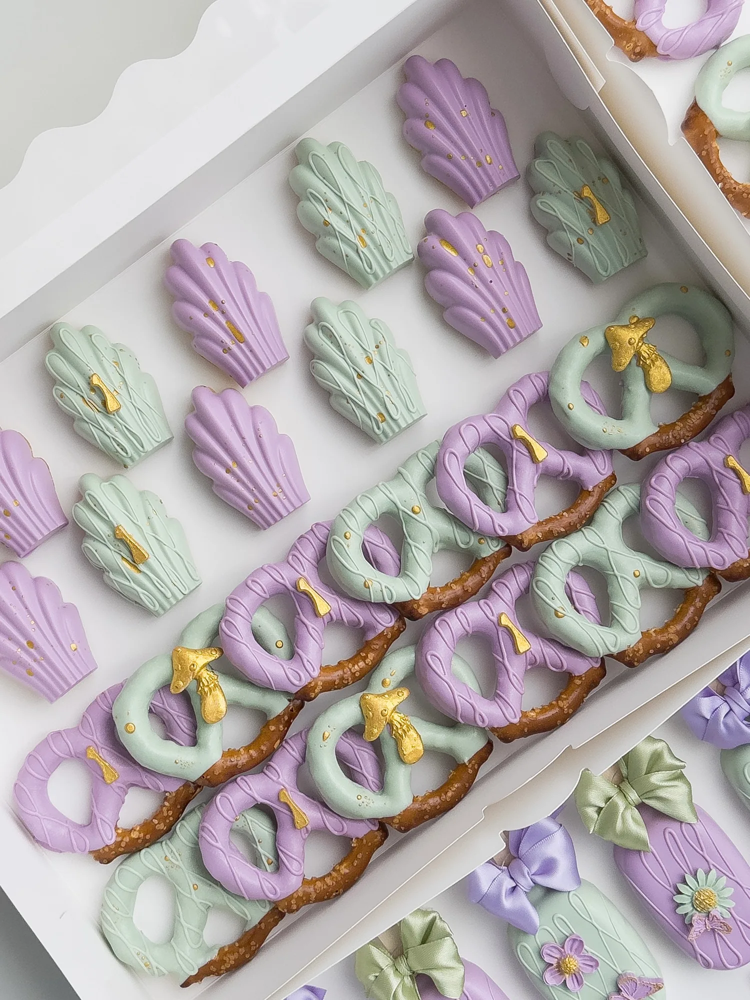 Lavender and sage dipped madeleines with small gold bows, lined up beside lavender and sage dipped pretzels.